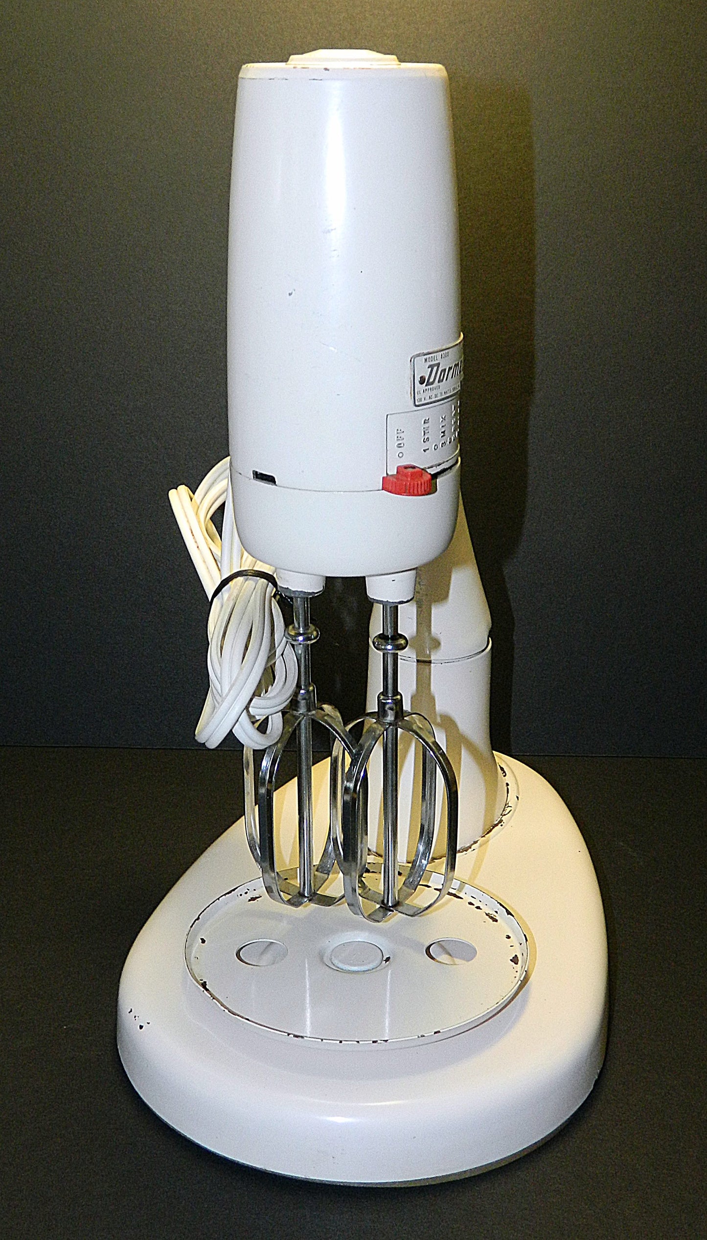 White electric mixer with attachments on a black background