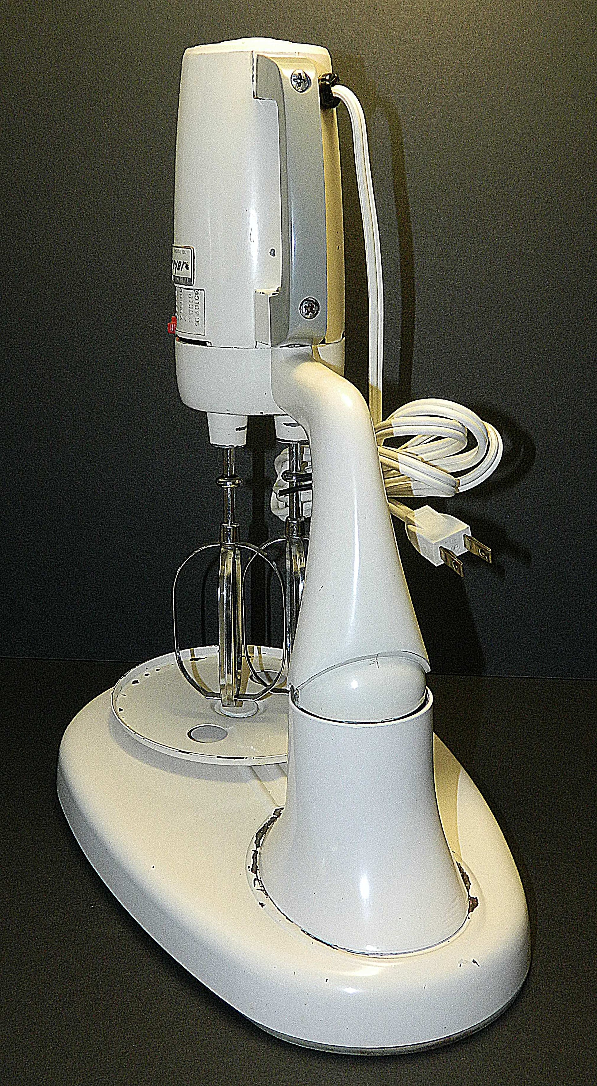 White stand mixer with attachments on a black background