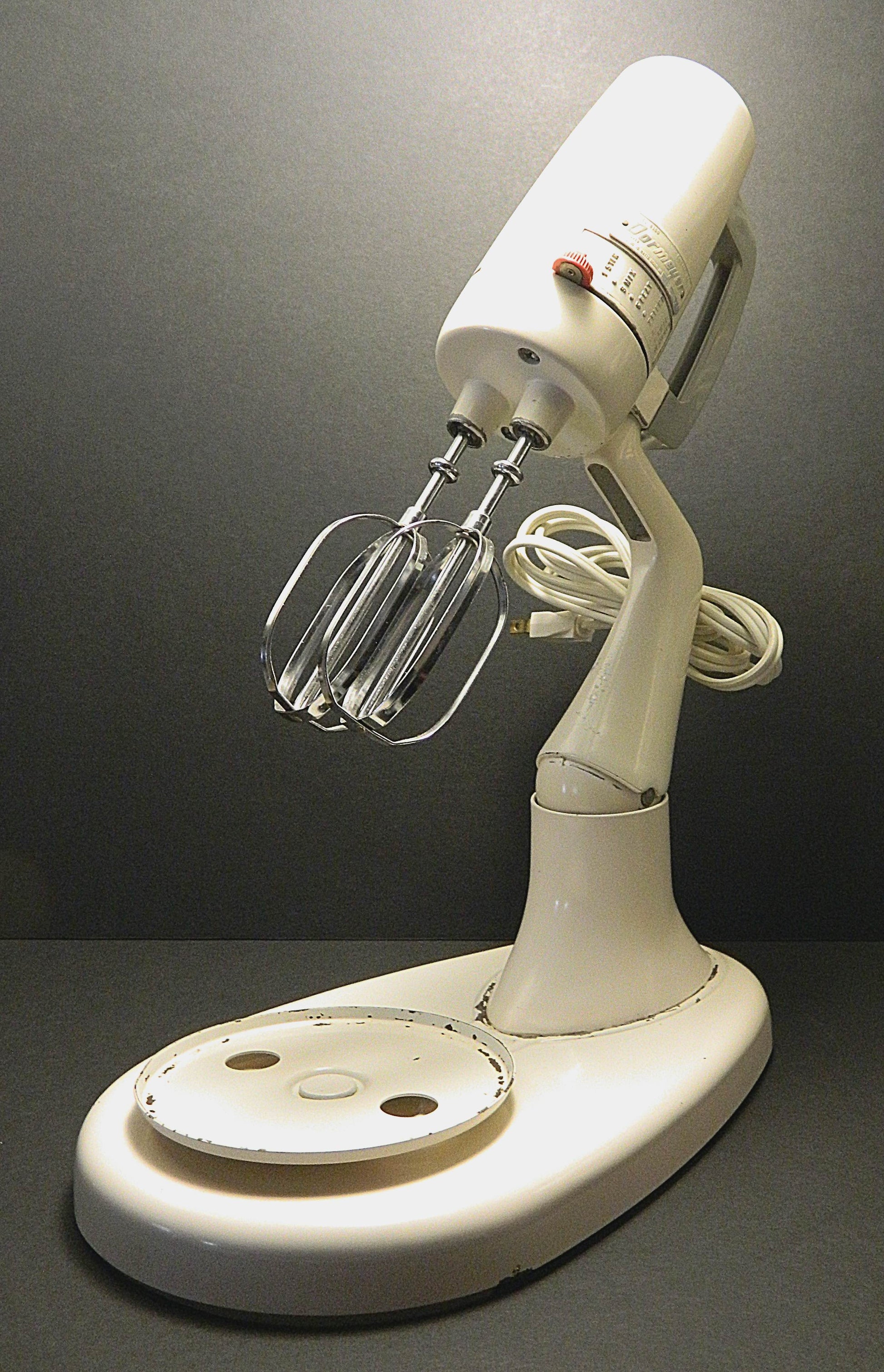 White stand mixer with attachments on a dark background