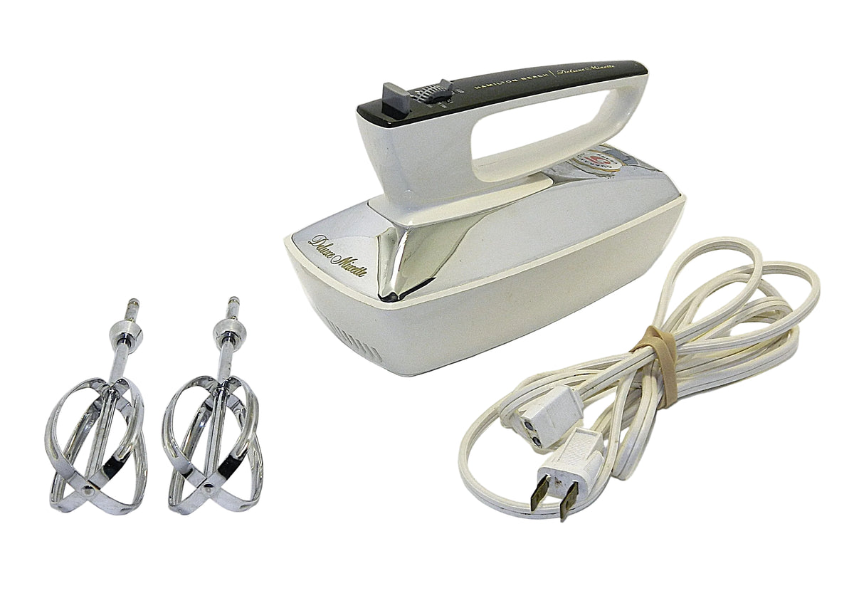 A vintage electric hand mixer with a cream-colored plastic body, chrome metal beaters, and a matching cream power cord, displayed on a white background.